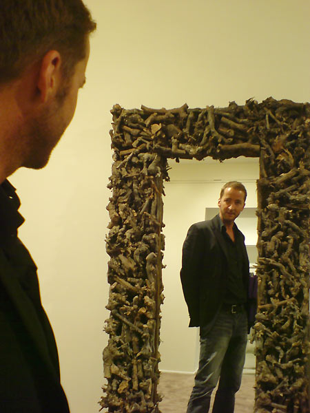 fig.: Wolfgang Olzinger in front of a mirror with a frame made of wild wood from the forest in the BR-Fashion Concept store. Wolfgang has found the mirror in Paris. In the new store it serves the customers at the 'Outdoor' section a quasi-authentic surrounding to check if the Geospirit jacket with the True Religion jeans is looking good in practice. I liked the way he is measuring himself in front of the mirror and captured the moment with the camera of my mobile.