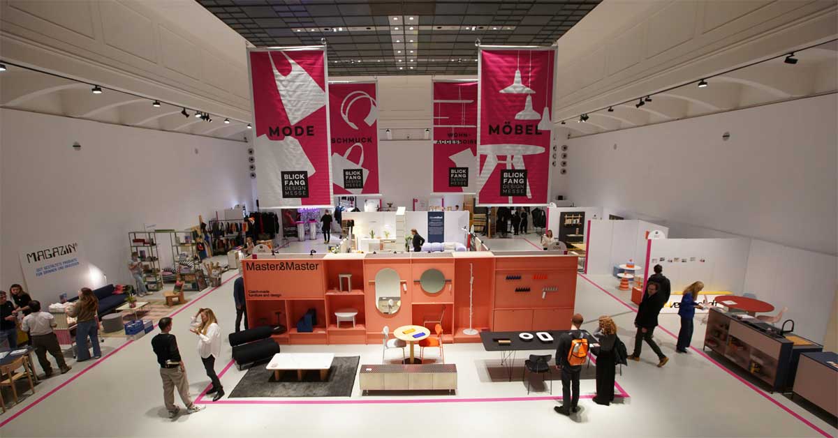Exhibition hall at MAK Vienna during Blickfang Designmesse with visitors exploring furniture, fashion, and jewelry displays.