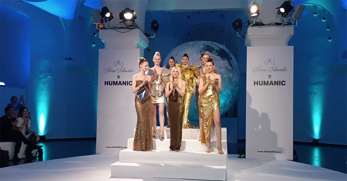 Image: The picture shows Silvia Schneider surrounded by models showcasing couture pieces from her latest collection, paired with shoes from the new Silvia Schneider x HUMANIC line. This photo was taken on April 2, 2025, during the presentation of the shoe collection at the Ovalhalle, Museumsquartier. Photo: © Fashion.at.
