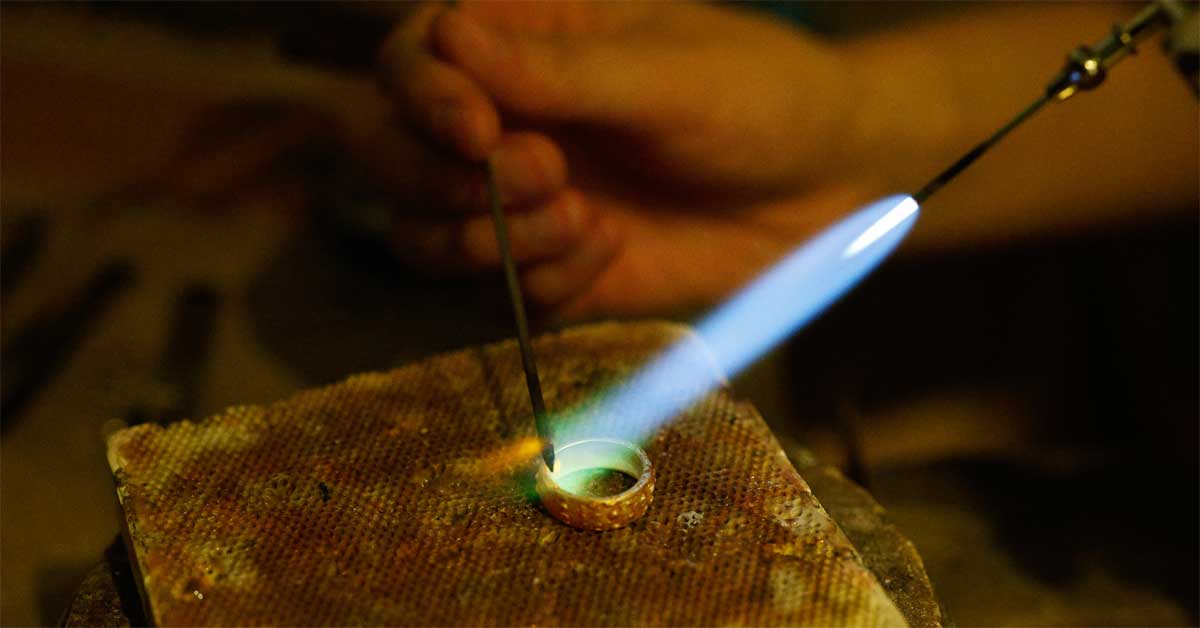 Jeweller at work shaping a ring by flame in an atelier workshop.