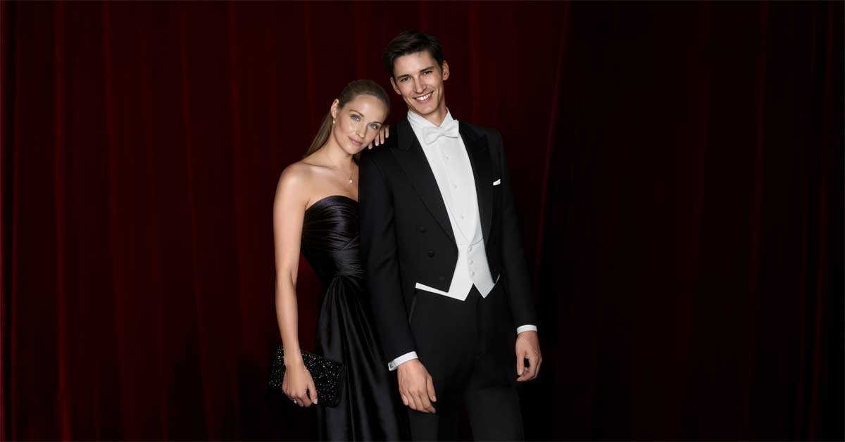 Campaign image of a woman in a black satin evening dress and a man in a black Wilvorst tailcoat for the Opera Ball partnership.