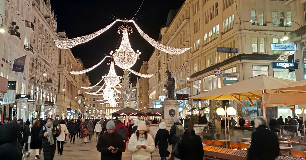 Crowds stroll along Vienna’s Graben under glowing chandelier Christmas lights on a December 2025 evening.