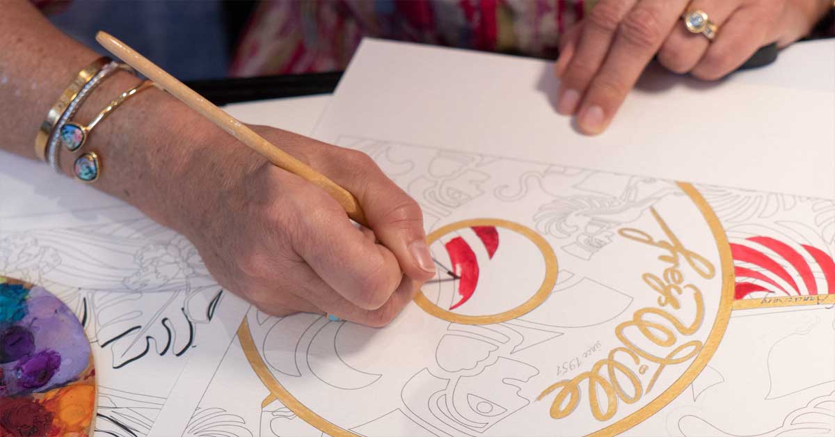 Close-up of an artisan painting a colourful enamel jewellery design by hand during Freywille’s 75th anniversary event in Vienna.