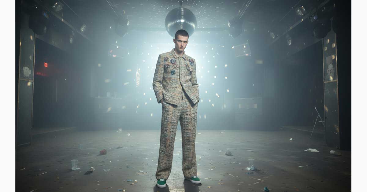 Model in bouclé jacket and trousers from Gina Drewes 'Last Days of Disco' menswear collection on nightclub dance floor.