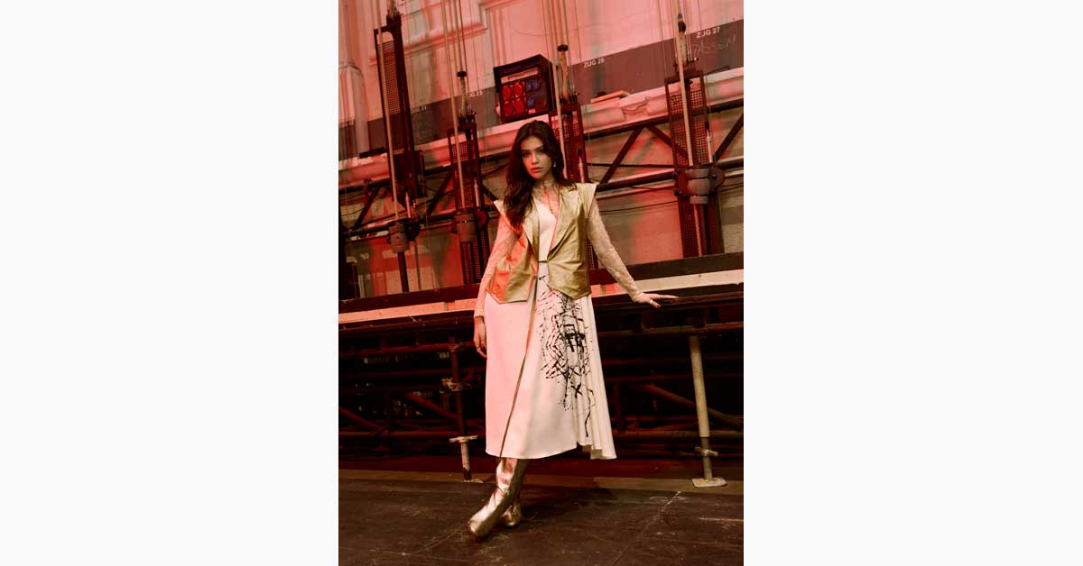 Model in industrial setting with red lighting wearing layered designer outfit at Halle E+G Vienna Fashion Week 2026 campaign image