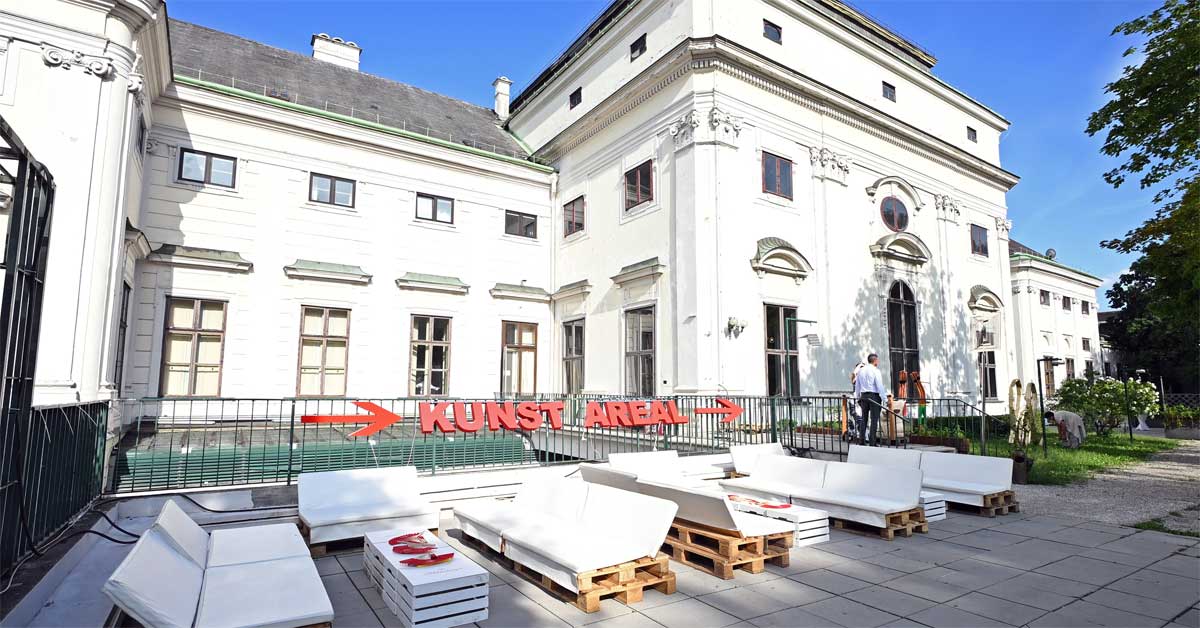 Lounge area at Palais Freiluft in the garden of Palais Auersperg in Vienna with seating and public-viewing venue signage.