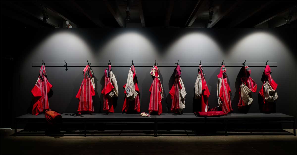Textile garments hanging in a gym-like space, referencing athletic rituals and cultural memory.