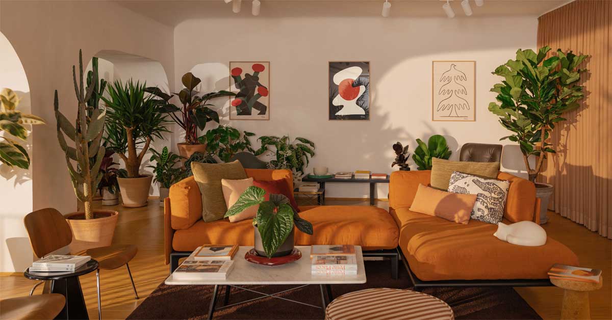 Living room with the Anagram Sofa by Panter&Tourron in orange, design chairs, and numerous indoor plants arranged in a modern, light-filled space.