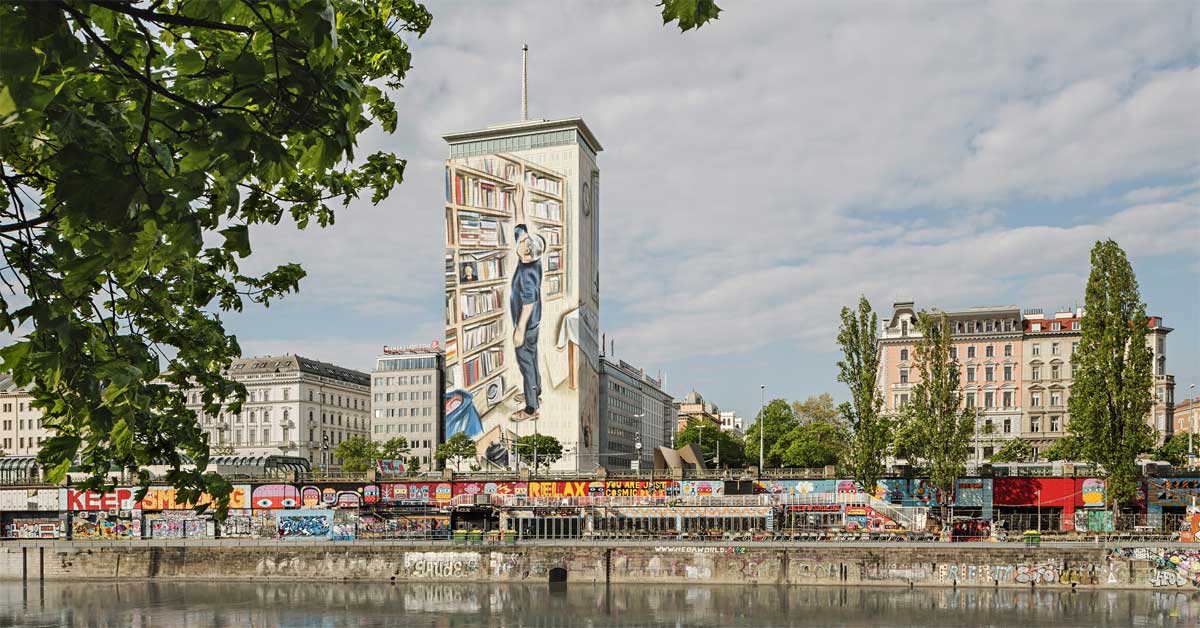 Ringturm covered in artwork showing bookshelves and a man reaching for a book; artwork by Marcin Maciejowski, photo by Hertha Hurnaus, rendering, Wiener Städtische Versicherungsverein.