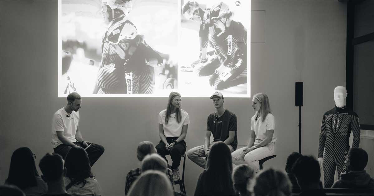 Four speakers on stage in front of a projected photo of ski mountaineers, discussing Austria’s preparations for the 2026 Winter Olympics during Martini Sportswear’s 'Road to Olympia' event in Annaberg, Salzburg.