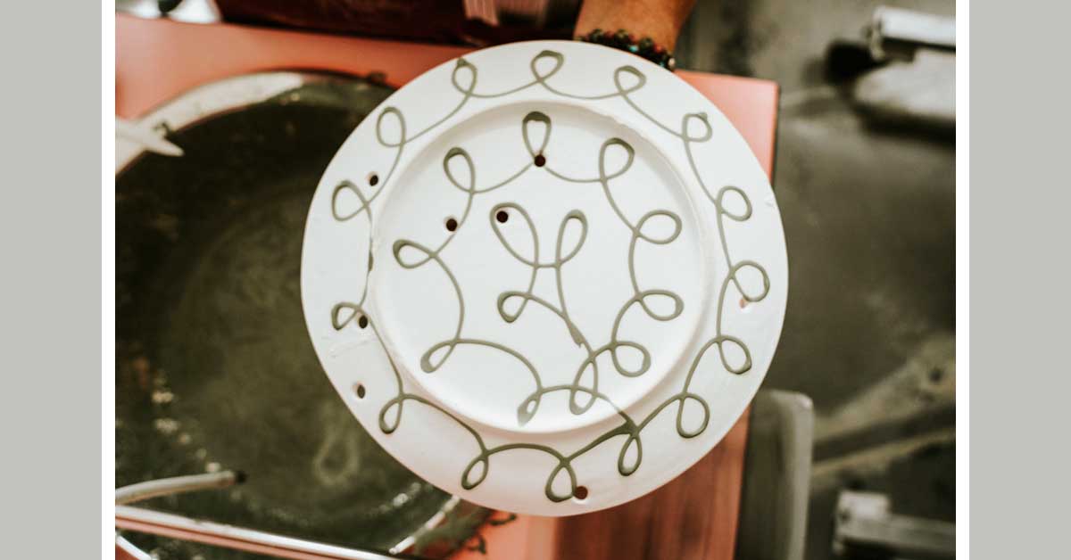 Hand-painted ceramic plate with green looping glaze pattern.