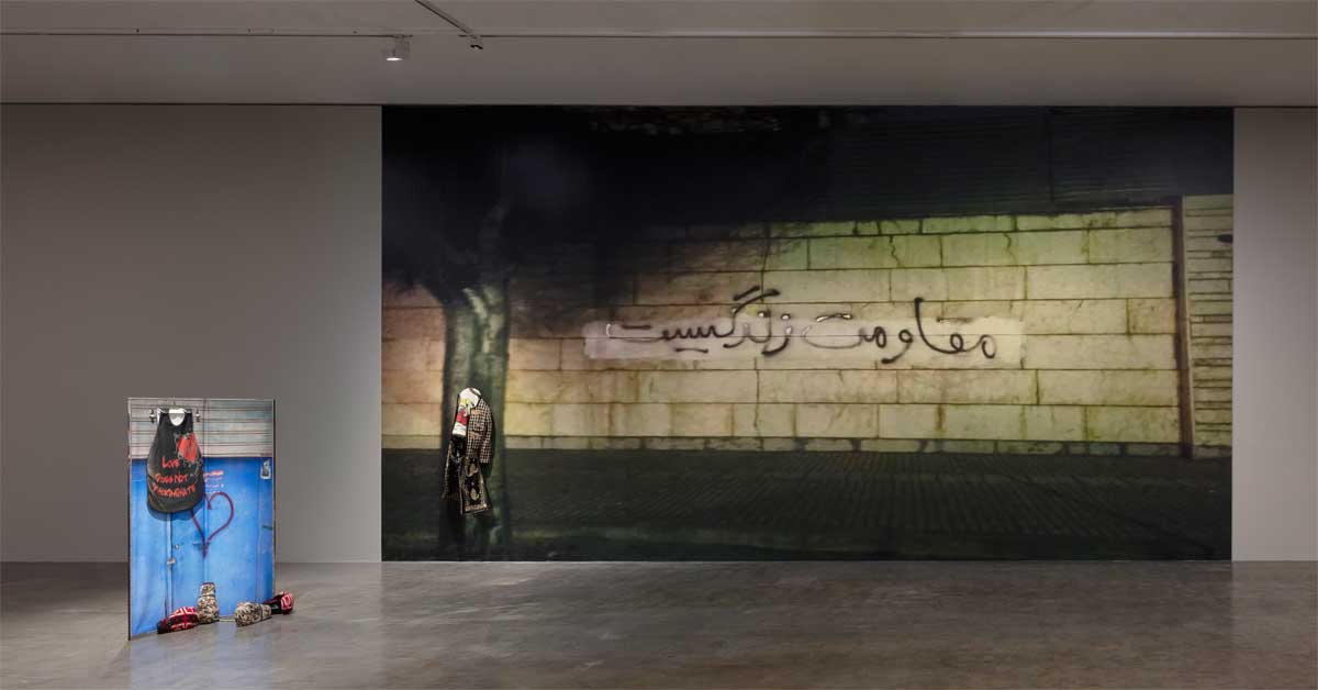 Installation view of Chalisée Naamani's exhibition 'Octogone' at Kunsthalle Wien, showing image-garments and a large wall projection.