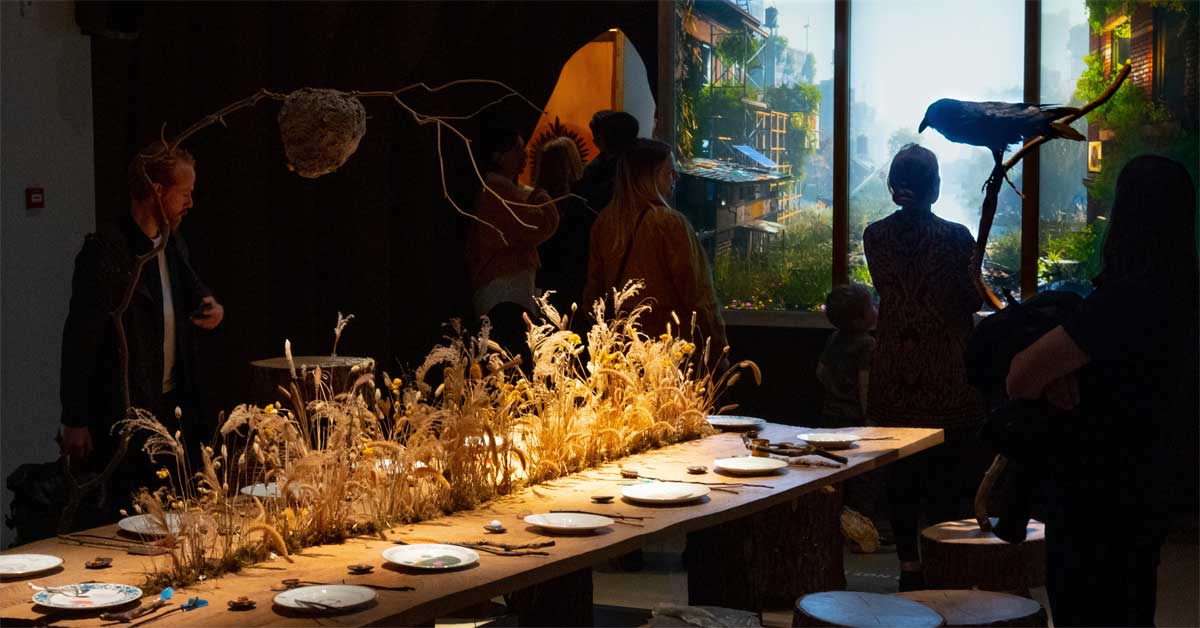 Installation with a long wooden table symbolising coexistence between humans, animals and plants.