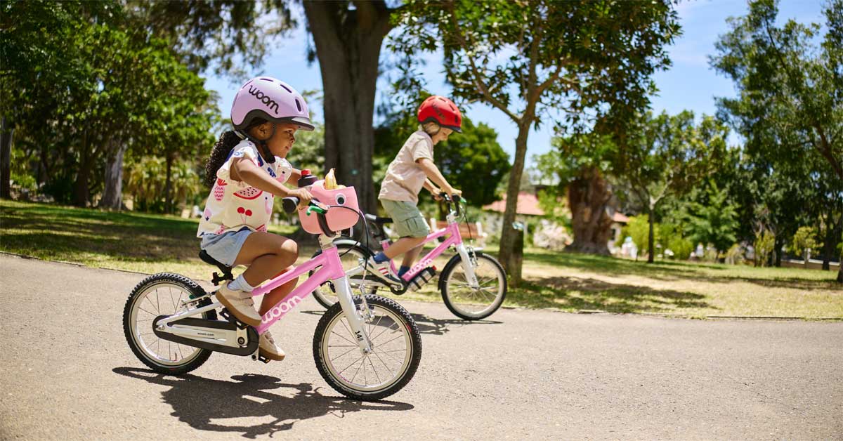 Children riding lightweight bikes on a park path during daylight, illustrating safe cycling for beginners.