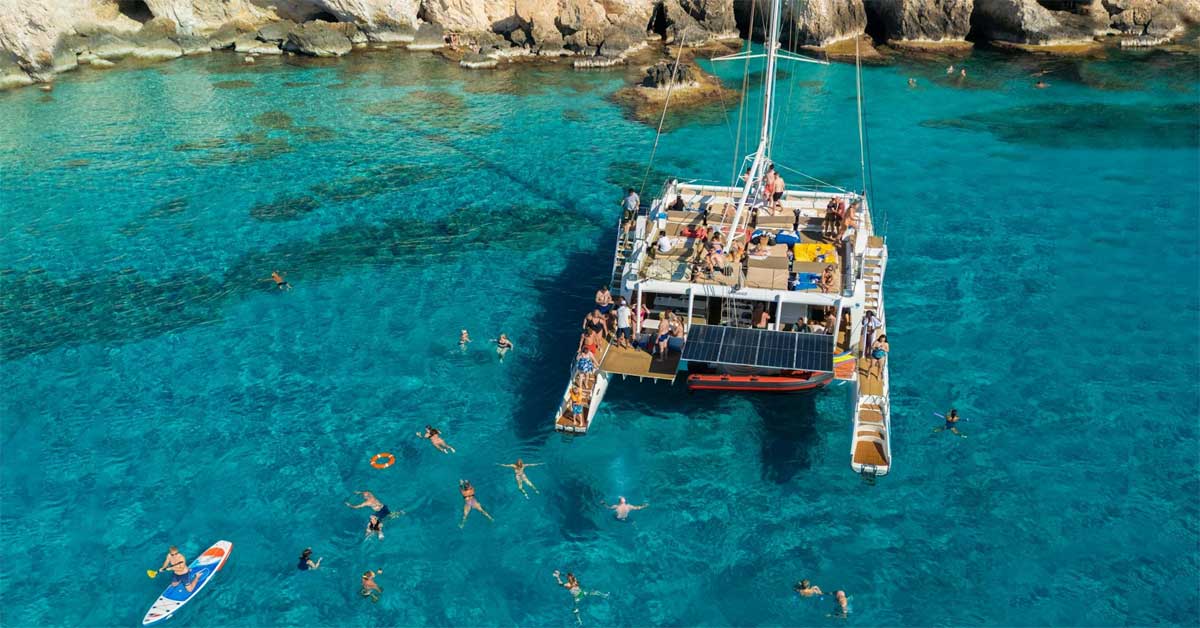 People swimming around a catamaran in turquoise coastal waters near Protaras, Cyprus, during a boat excursion.